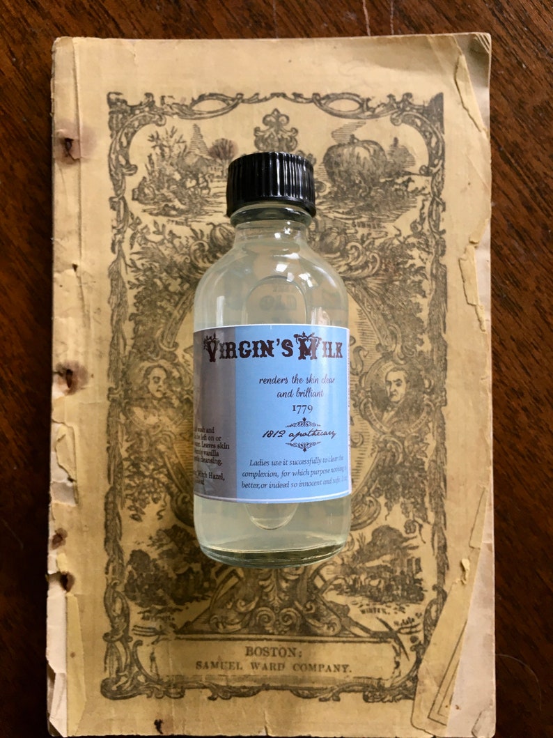 May include: A clear glass bottle with a black cap labeled "Virgin's Milk" and the text "renders the skin clear and brilliant 1779 1812 apothecary Ladies use it successfully to render the complexion, for which purpose nothing is better, or indeed so innocent and safe." The bottle is sitting on a vintage book with a decorative design.