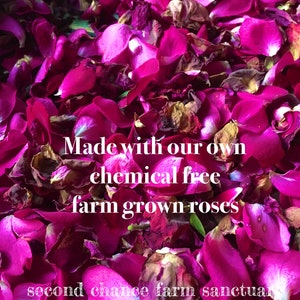 Op de afbeelding: Close-up van een stapel diep roze rozenblaadjes. De blaadjes zijn gedroogd en hebben een licht gerimpelde textuur. De tekst "Made with our own chemical free farm grown roses" is over de afbeelding gelegd. De tekst "second chance farm sanctuary" is zichtbaar onderaan de afbeelding.