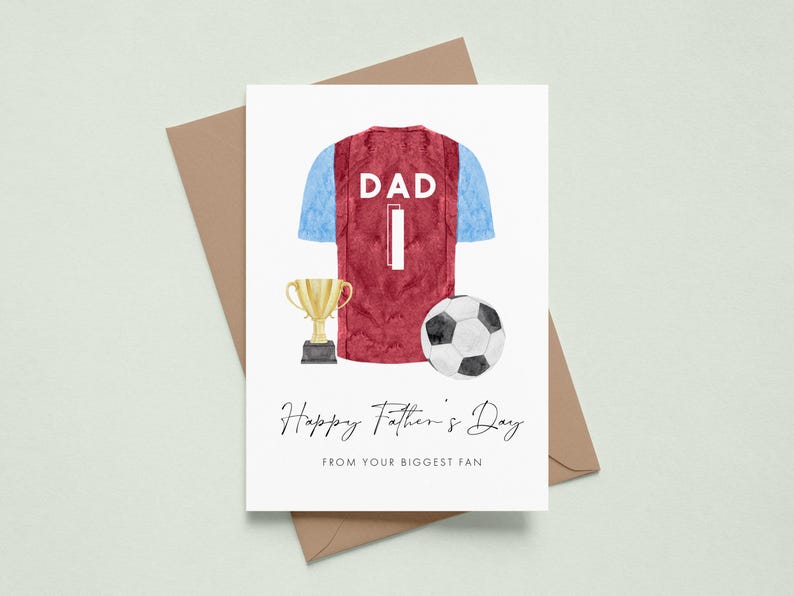 May include: A Father's Day card featuring a watercolor illustration of a burgundy and blue soccer jersey with the word "DAD" and the number "1". A gold trophy and a soccer ball are also depicted. The card reads "Happy Father's Day FROM YOUR BIGGEST FAN".