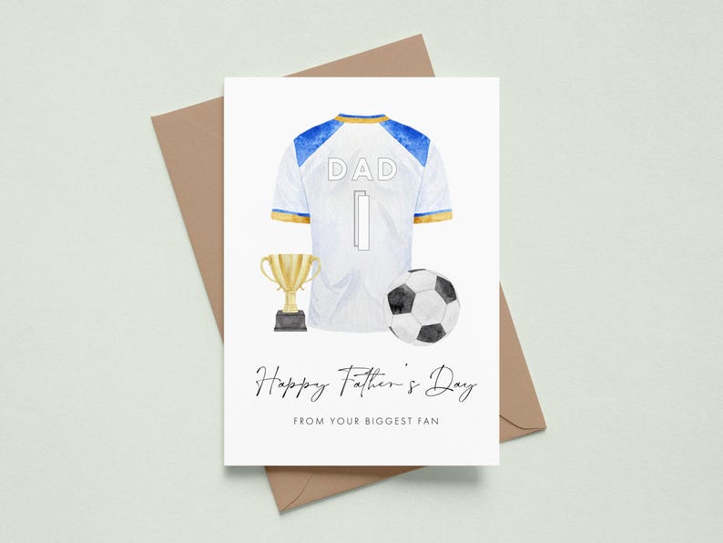 May include: A Father's Day card featuring a watercolor illustration of a soccer jersey with the word "DAD" and the number "1". A soccer ball and a trophy are also depicted. The card reads "Happy Father's Day FROM YOUR BIGGEST FAN".