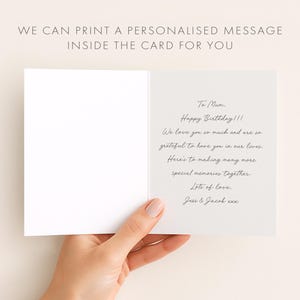 May include: An open white greeting card with handwritten text inside, held by a hand. The text reads "To Mum, Happy Birthday!!! We love you so much...Lots of love, Jess & Jacob xxx." The card's top text says "WE CAN PRINT A PERSONALISED MESSAGE INSIDE THE CARD FOR YOU."