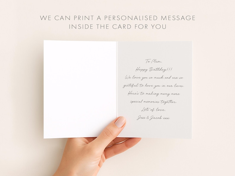 May include: An open white greeting card with handwritten text inside, held by a hand. The text reads "To Mum, Happy Birthday!!! We love you so much...Lots of love, Jess & Jacob xxx." The card's top text says "WE CAN PRINT A PERSONALISED MESSAGE INSIDE THE CARD FOR YOU."