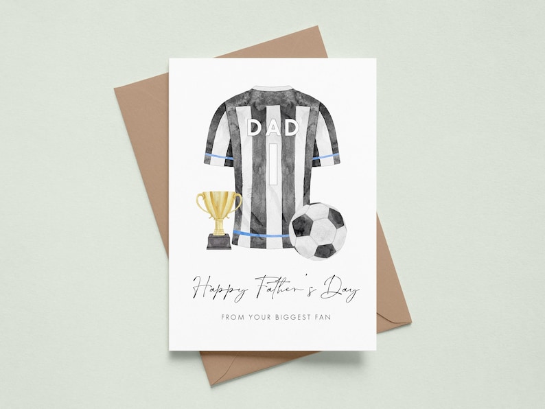 May include: A Father's Day card with a watercolor illustration. The card features a black and white striped soccer jersey with the word "DAD" and the number 1. A gold trophy and soccer ball are also depicted. The text reads "Happy Father's Day from your biggest fan."