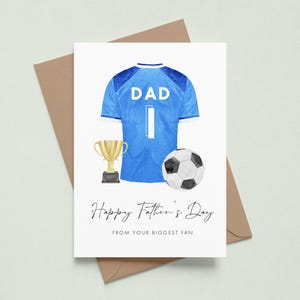 May include: Father's Day greeting card featuring a blue soccer jersey with the word "DAD" and the number "1". A gold trophy and a black and white soccer ball are also depicted. The card reads "Happy Father's Day FROM YOUR BIGGEST FAN."