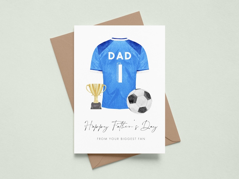 May include: Father's Day greeting card featuring a blue soccer jersey with the word "DAD" and the number "1". A gold trophy and a black and white soccer ball are also depicted. The card reads "Happy Father's Day FROM YOUR BIGGEST FAN."