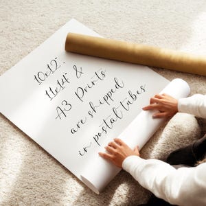 A person is holding a roll of paper and appears to be preparing to print or roll it.