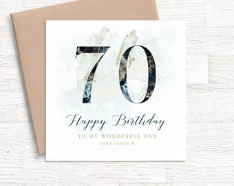 May include: A square greeting card featuring the number 70 in a dark blue and gold marbled texture. Below the number, the text reads Happy Birthday, TO MY WONDERFUL DAD, and LOVE JAMES X. The card is paired with a light brown envelope.