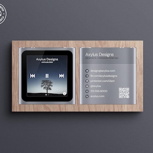 May include: A wooden sign with two silver panels. The left panel shows a mock-up of a music player with a tree silhouette on the screen. The right panel has the text "Axylus Designs" and contact information, including a QR code.
