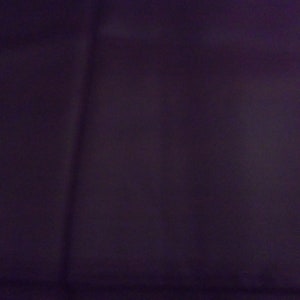 May include: A solid dark purple fabric background.