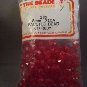 May include: A bag of 8mm red faceted beads. The bag is labeled "THE BEADY CRAFT PRODUCTS 135 8mm 710A FACETED BEAD 017 RUBY MADE IN USA. HOPE VALLEY, RI 02832"