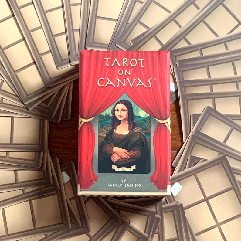 May include: A red box with the text "Tarot on Canvas" and a picture of the Mona Lisa on the front. The box is surrounded by a pile of brown picture frames.