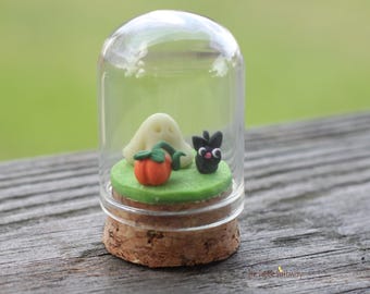 Micro gato negro, fantasma que brilla en la oscuridad y pequeña calabaza en una pequeña campana