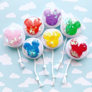 Pu&ograve; includere: Una collezione di ornamenti rotondi in feltro a forma di Mickey Mouse. Ogni ornamento presenta una silhouette di Mickey Mouse di colore diverso, circondata da plastica trasparente riempita di glitter iridescenti. Cordini bianchi con nappe pendono da ogni ornamento.