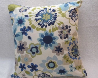 May include: Square decorative pillow with a floral pattern. The pillow features a cream-colored background with a repeating pattern of blue, navy, gray, and green flowers. The pillow's edges are neatly finished, and the overall design is modern and stylish.
