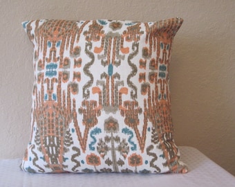 May include: Square throw pillow with a white background and a repeating pattern in shades of orange, brown, gray, and teal. The pillow has a soft, textured appearance and is likely made of fabric.