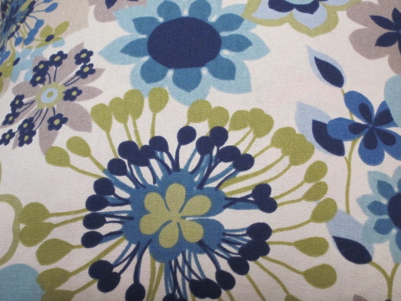 May include: Close-up of a floral pattern featuring large stylized flowers in shades of blue, green, and gray against a white background. The design has a retro, mid-century modern aesthetic, with a repeating pattern.