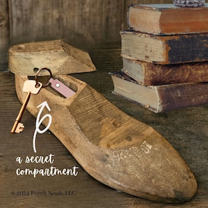 May include: A wooden shoe with a secret compartment, revealed by lifting the top. A key is in the compartment, and the words "a secret compartment" are written below the shoe. The shoe is on a wooden surface.