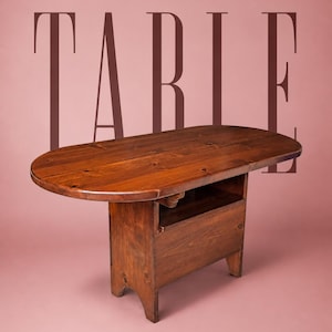 May include: A dark brown wooden table with an oval top and a rectangular base featuring an open storage shelf. The word TABLE is printed in large, dark brown capital letters behind the furniture piece against a solid pink background.