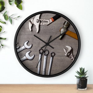 Peut inclure: Une horloge noire avec un fond en bois grainé représentant divers outils, dont des clés, un marteau et une pince.