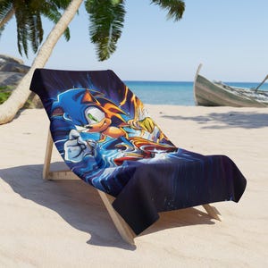 Peut inclure: Une serviette de plage illustrant Sonic le Hérisson en bleu et jaune courant avec un effet de flou bleu et blanc en arrière-plan.