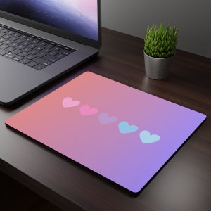 Peut inclure: Un tapis de souris à dégradé rose et violet avec cinq cœurs alignés. Les cœurs sont roses, bleus et bleu clair.