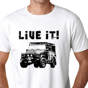 May include: White t-shirt with a black and white graphic of a Land Rover Defender with the text "LIVE IT!" printed on the front.