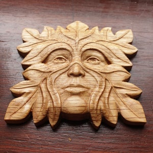 May include: A wooden carving of a Green Man, a mythical figure often associated with nature and the forest. The carving is detailed and realistic, with a face framed by leaves and branches.