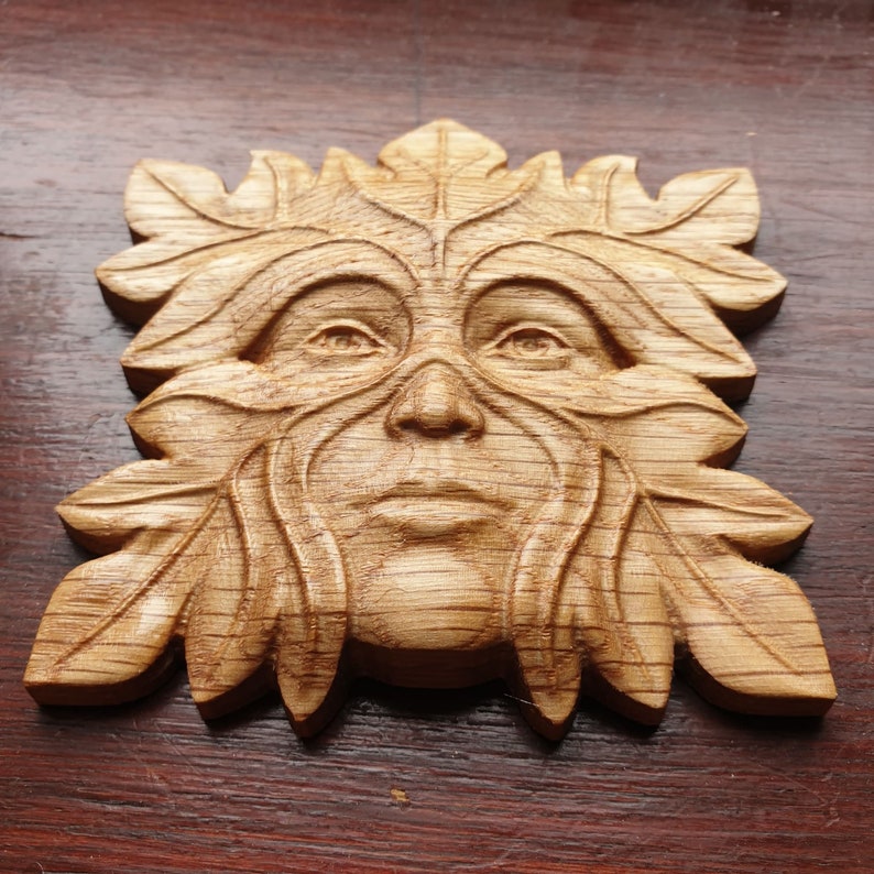 May include: A wooden carving of a Green Man, a mythical figure often associated with nature and the forest. The carving is detailed and realistic, with a face framed by leaves and branches.