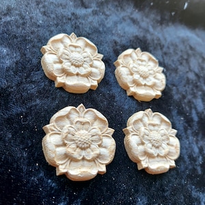 May include: Four wooden rose carvings, each with a detailed design and a light brown colour.