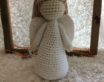 May include: A crocheted angel figurine with white wings and a white dress. The angel has a light brown yarn hair.