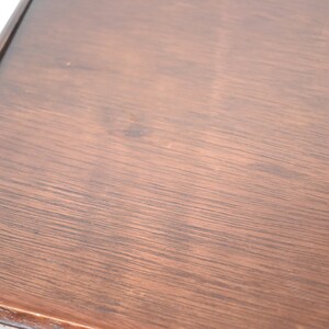 Pode incluir: Close-up de um tampo de mesa de madeira marrom escuro com uma superf&iacute;cie lisa e ligeiramente texturizada.