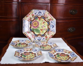 Può includere: Un set di cinque piatti ottagonali in porcellana con un motivo floreale. I piatti sono decorati con una varietà di colori, tra cui blu, rosso, verde e giallo. I piatti sono disposti su una tovaglia bianca.