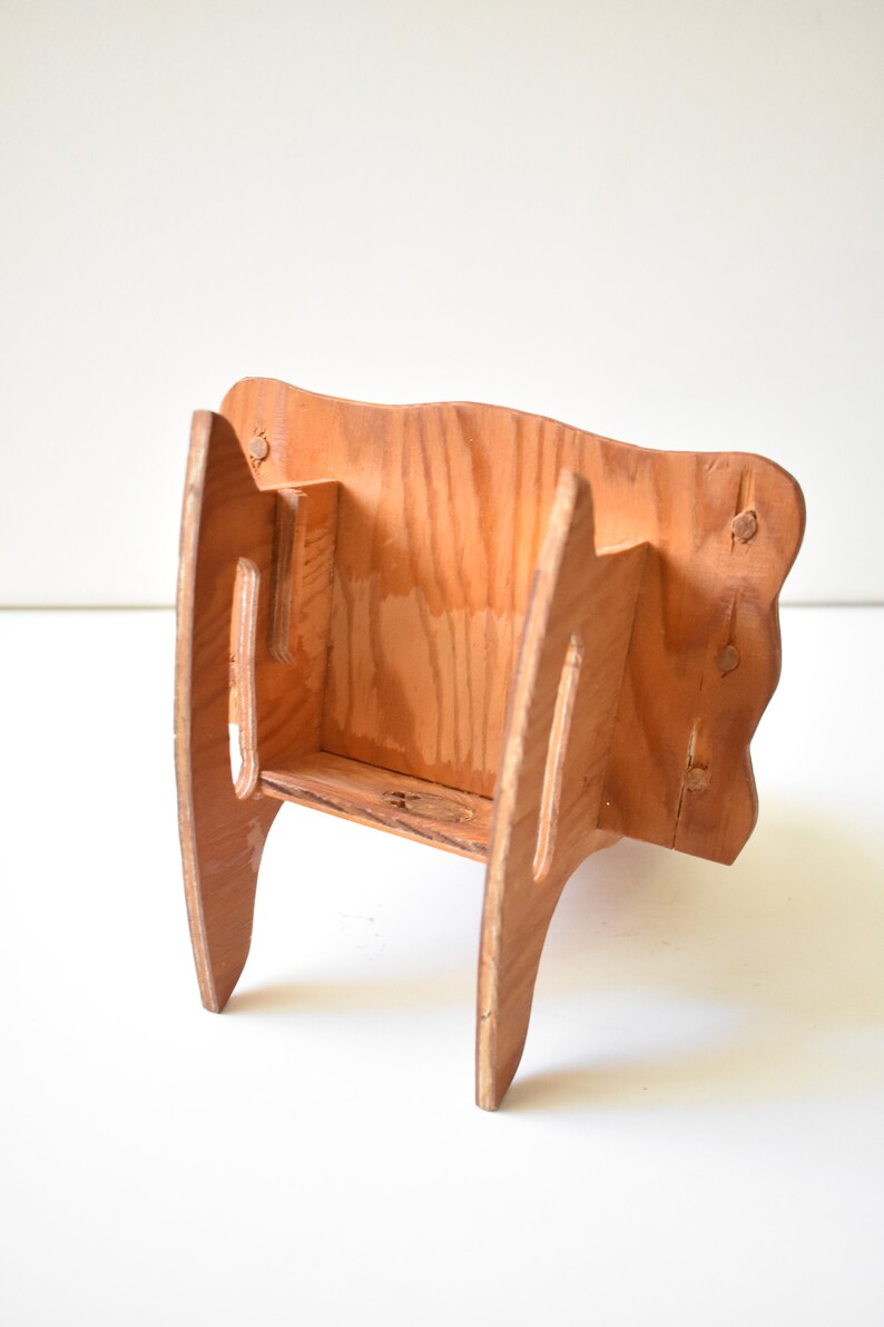 May include: A wooden shelf unit with a simple design. The shelf is made of light brown wood and has a rectangular shape. The shelf has two shelves and is supported by two legs on each side.