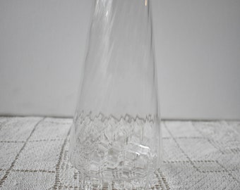 May include: A clear glass vase with a textured, swirling design. The vase has a wide base and a narrow opening.