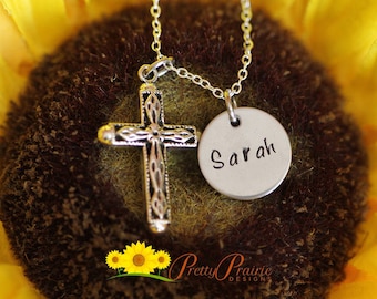 May include: Silver necklace with a cross pendant and a round charm with the name "Sarah" engraved on it. The necklace is displayed against a sunflower background.