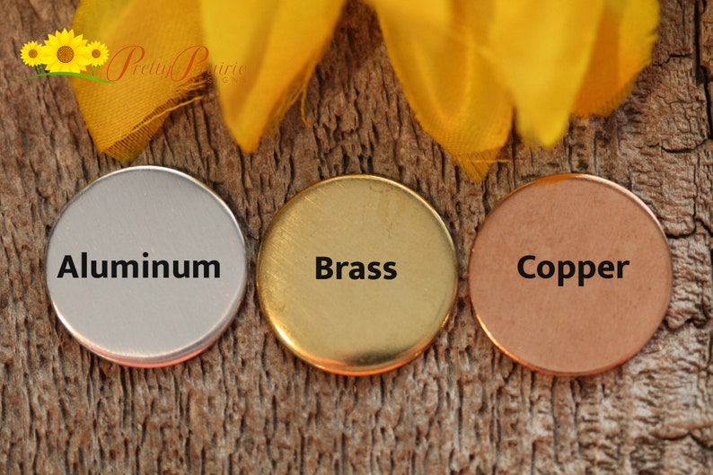 May include: Three round metal discs, each with a different finish: aluminum, brass, and copper. The discs are arranged horizontally on a wooden surface.