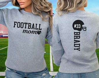 May include: Grey sweatshirt with the text "FOOTBALL mom" and a football graphic on the front. The back of the sweatshirt has the text "BRADY" and the number "#33" with a football helmet graphic.