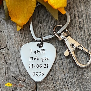 May include: Silver guitar pick keychain with the text "I still pick you 11.06.21 D♥K" engraved on it.