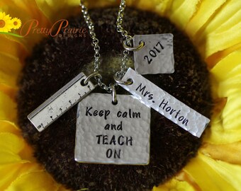 May include: Silver necklace with four charms: a ruler, a square charm that says "Keep calm and TEACH ON", a rectangular charm that says "Mrs. Horton", and a square charm that says "2017".