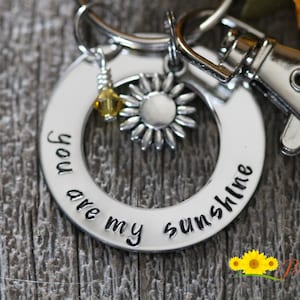 May include: Silver keychain with a round charm that says "You are my sunshine" and a small silver sunflower charm.