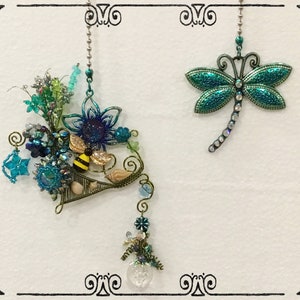 May include: Two decorative light pull chains. One features a blue and green dragonfly with rhinestones. The other features a bee, flowers, and other blue and green embellishments.