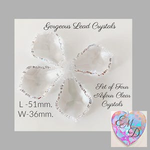 May include: A set of four clear Asfour lead crystals with faceted edges. The text reads Gorgeous Lead Crystals, Set of Four Asfour Clear Crystals, L-51mm, W-36mm. A small heart-shaped tag with iridescent patterns and the letters EMD is included.
