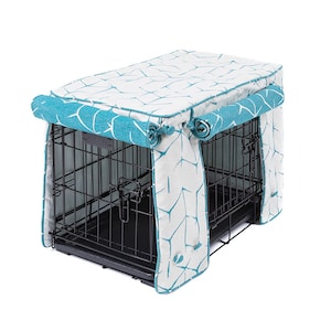 May include: A teal and white patterned dog crate cover with rolled edges. The cover is made of fabric and has a zipper closure. The cover is designed to fit over a standard dog crate.