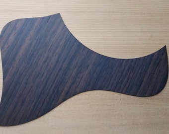 May include: A dark brown wood guitar pickguard with a unique grain pattern.