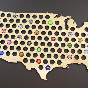 May include: A wooden map of the United States with a circular cutout for each state. The cutouts are filled with bottle caps of various colors and designs.