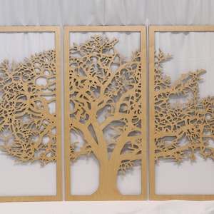 May include: Three-panel wooden wall art featuring a tree design. Each panel has a light brown frame with a tree cut-out in the center. The tree's branches and leaves are intricately detailed, creating a natural and artistic aesthetic. The panels are displayed against a white background.