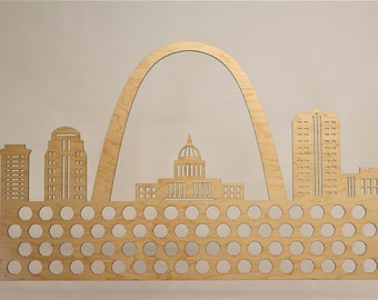Puede incluir: Arte de pared de madera con una silueta del horizonte de St. Louis, que incluye el Arco Gateway, el Antiguo Palacio de Justicia y otros edificios. La obra de arte tiene una cuadrícula de 60 porta-tapones.