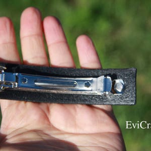 May include: A black rectangular hair barrette with a silver metal clasp. The barrette is held in a hand, with the website Evicraft.com visible in the bottom right corner.