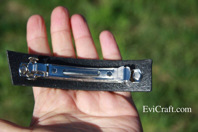 May include: A black rectangular hair barrette with a silver metal clasp. The barrette is held in a hand, with the website Evicraft.com visible in the bottom right corner.