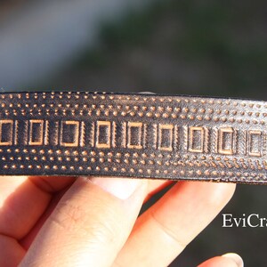 May include: A dark brown leather hair barrette with a rectangular design and brass rivets. The barrette features a repeating pattern of small dots and rectangular shapes. The website Evicraft.com is visible.